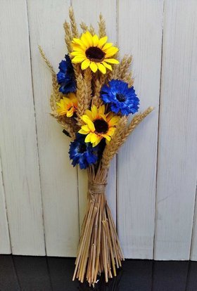 A bouquet of artificial flowers with ears of cereals, sunflowers and cornflowers